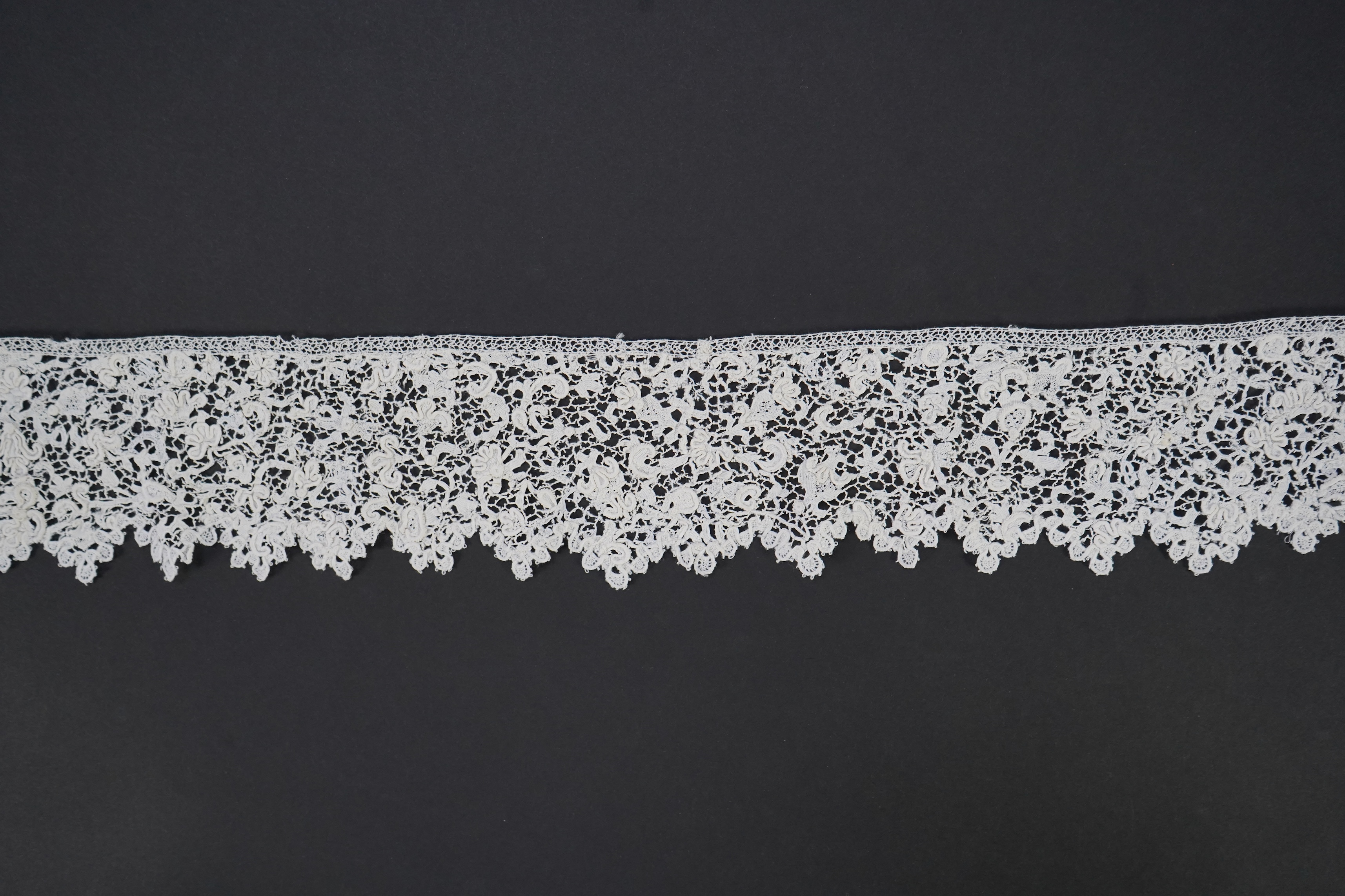 A late 17th century wide flounce of Point de France needle lace, together with a narrower flounce, both with raised elements of the design in the style of Point de Rose, but less so. This lace was very popular with the F